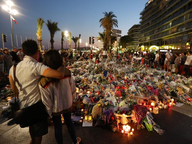 People stand in front of flowers, candles and messages laid at a makeshift memorial in Nice. Picture: AFP/Valery Hache