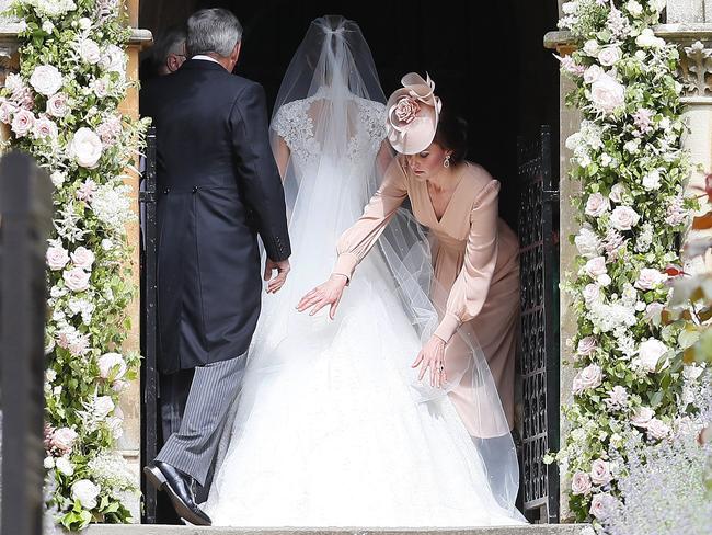 Duchess of Cambridge arranges the train of her sister Pippa Middleton’s dress. Picture: AP Photo/Kirsty Wigglesworth, Pool