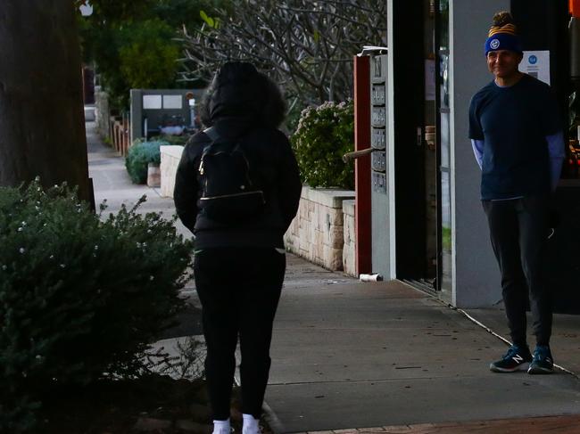 Ms Berejiklian standing away from the cafe while Mr Moses waits for coffee.