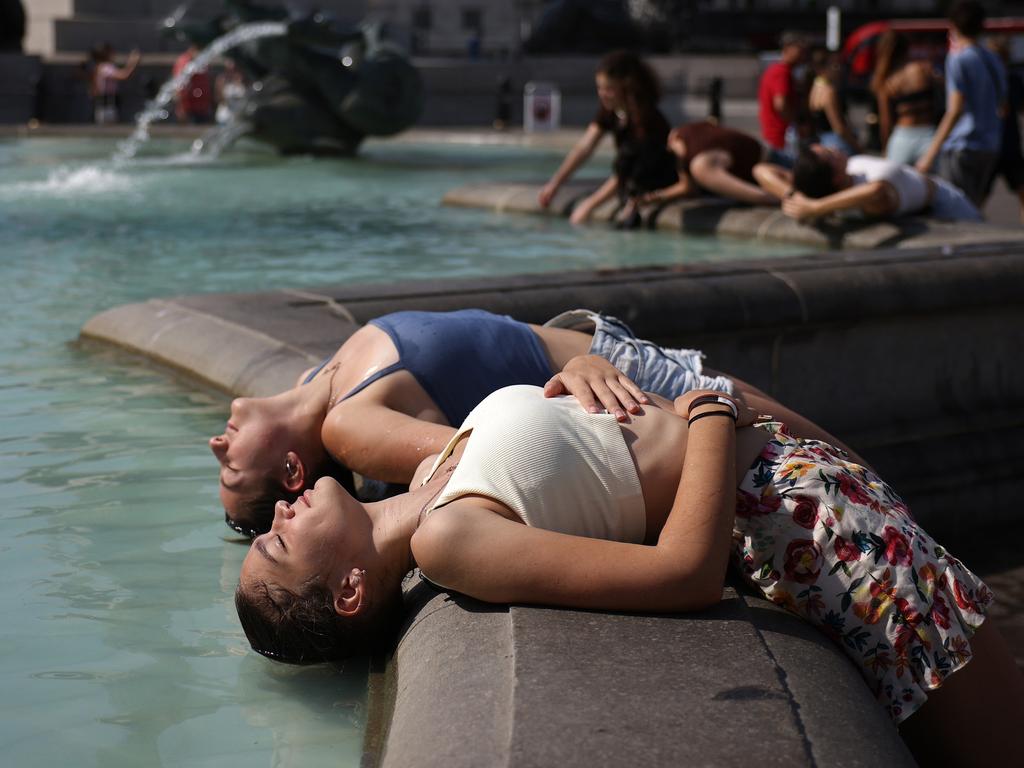 Two women dip their heads into the fountain to cool off in Trafalgar Square in London. Picture: Getty Images