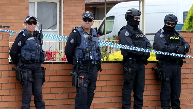 Heavily armed officers line Gentles Avenue after the raids. Picture: David Geraghty