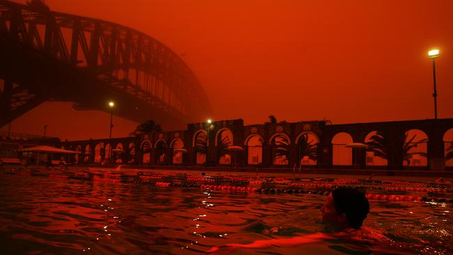 Swimmers take an early dip at North Sydney Pool as a red haze blankets Sydney from a dust storm brought to the coast by overnight winds.