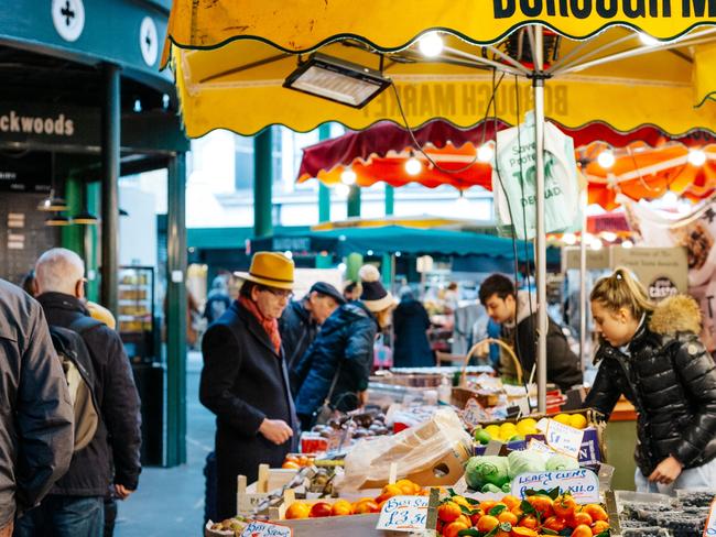 London, UK - 4 March, 2022: color image depicting a market stall workers in Borough Market, London, UK. The stalls are selling a variety of fresh fruit and vegetables. Borough Market is one of the oldest and most popular food markets in the UK and globally. Colour image with copy space.