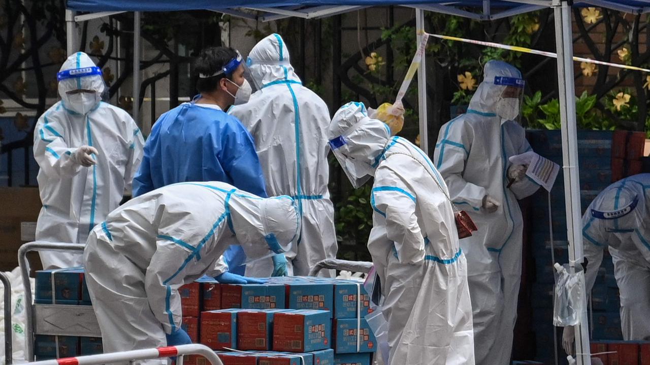 Workers wearing personal protective equipment (PPE) are seen next to food delivered by the local government for residents in a compound. Picture: AFP