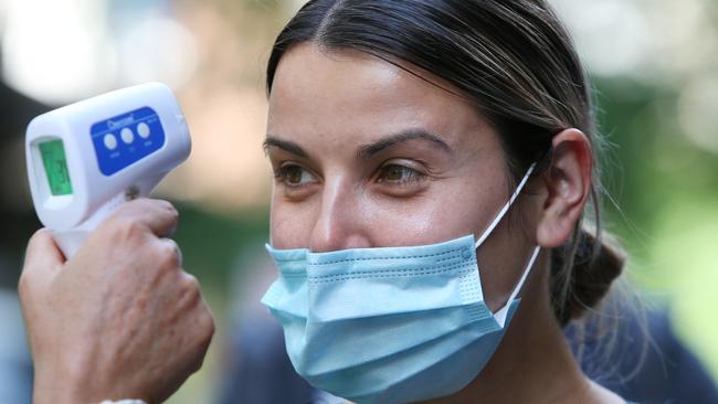 A healthcare worker conducts a temperature test as people arrive to check in at a Covid-19 Vaccination hub in Sydney. Picture: Lisa Maree Williams/Getty Images