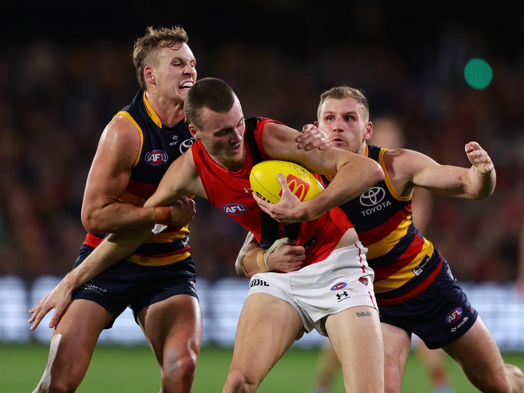 Nik Cox is wrapped up by Jordan Dawson and Rory Laird. Picture: Sarah Reed/AFL Photos via Getty Images