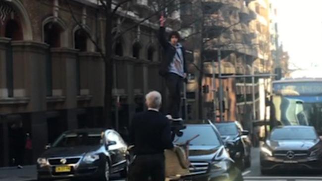 The city worker stands in front of the car with a chair waiting for the knifeman. Picture: Seven News