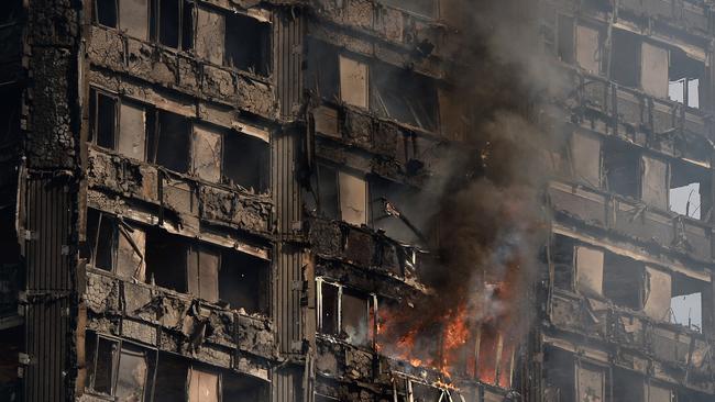 Debris falls from the burnt out building as dawn breaks. Picture: Getty Images.