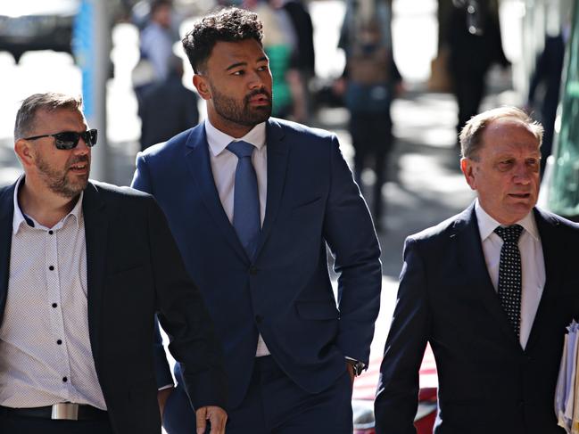 Zane Musgrove (blue suite) and his supporters enter the Downing Centre today. Picture: Adam Yip