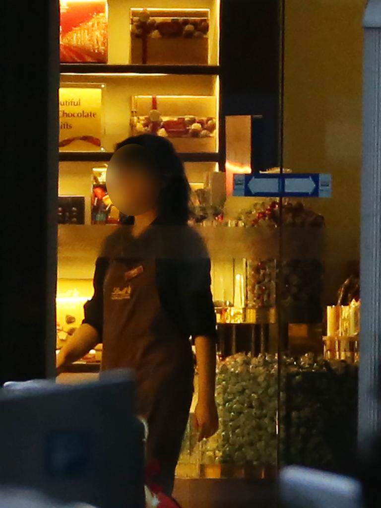 A staff member goes to the front door to turn off the lights in the Lindt cafe during the siege. Picture: Craig Greenhill