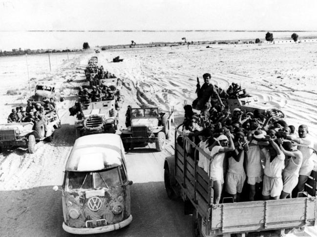 Truckload of Egyptian prisoners pass an Israeli armoured column near El Arish during the Six Day War.