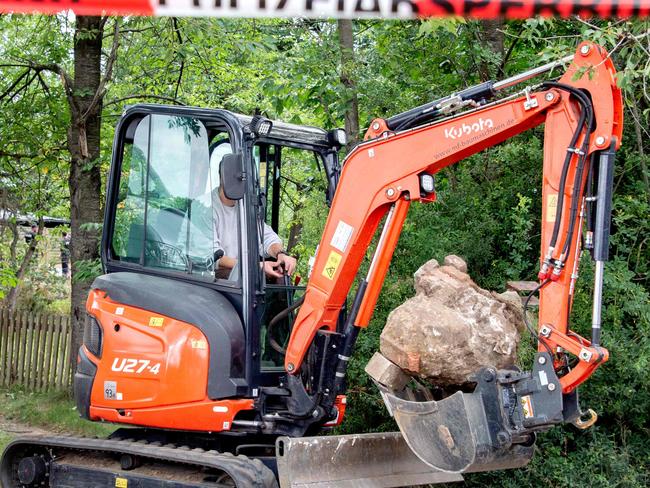 An excavator removes stone as police officers search a garden allotment in the northern German city of Hanover on July 28, 2020, in connection with the disappearance of British girl Madeleine McCann. - Police revealed in June that they were investigating a 43-year-old German man over the 2007 disappearance of three-year-old "Maddie", saying they believe he killed her. Madeleine went missing from her family's holiday apartment in the Portuguese holiday resort of Praia da Luz on May 3, 2007, a few days before her fourth birthday, as her parents dined with friends at a nearby tapas bar. (Photo by Hauke-Christian Dittrich / AFP)