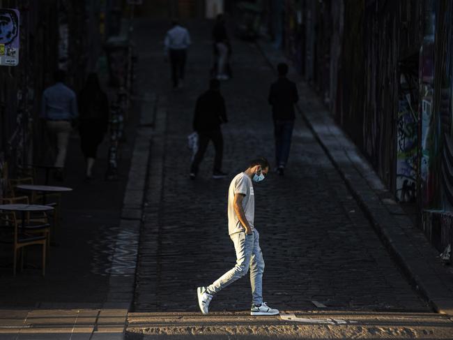 MELBOURNE, AUSTRALIA - DECEMBER 10: A man walks past Hosier Lane wearing a face mask on December 10, 2020 in Melbourne, Australia. Victoria has recorded its 41st day without any new COVID-19 cases, with no one diagnosed with coronavirus since 30 October in Victoria. Mask-wearing is now only mandatory in indoor shopping centres and public transport, including rideshares and taxis, but relaxed in other settings. Victorians must still carry a mask with them at all times and wear it when a physical distance of 1.5 metres cannot be maintained, but mask use is encouraged, but not mandatory, in other situations. Cafes, restaurants and pubs can double their patron numbers to a maximum of one person per 2 sq m and nightclubs can reopen from midnight. People are able to have up to 30 visitors at home, while outdoor gatherings can now have up to 100 people. (Photo by Daniel Pockett/Getty Images)