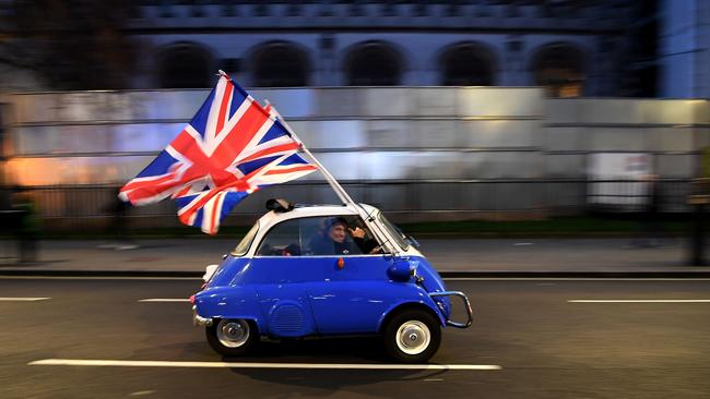 A man waves Union flags from a BMW Isetta as he drives past Brexit supporters gathering in Parliament Square, in central London in January. Picture: AFP