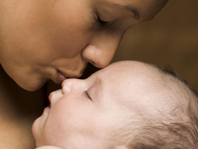 Relationship portrait of a young adult mother as she holds and kisses her newborn baby. Generic image.