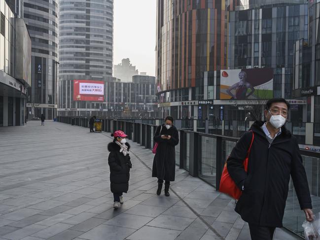 A Chinese family wears protective masks as they walk in an empty shopping area in Beijing. Picture: Getty