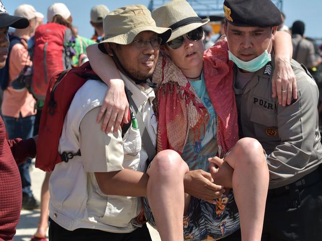 A foreign tourist (C) is given assistance as evacuated tourists arrive from nearby Gili Trawangan island at the port at Bangsal in northern Lombok. Picture: AFP