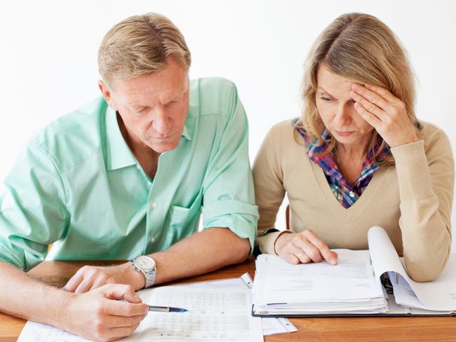 Middle aged couple sitting together at table and going through monthly expenses bills. They are experiencing stress. Picture: iStock.