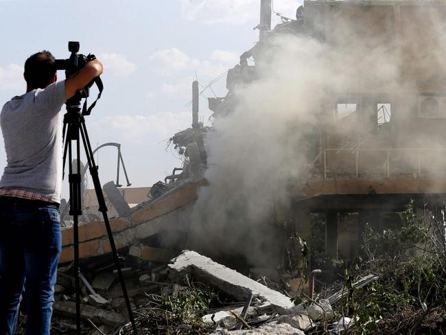 A journalist films the wreckage of a building described as part of the Scientific Studies and Research Centre (SSRC) compound in the Barzeh district, north of Damascus, after the missile strike. Picture: AFP Photo/Louai Beshara