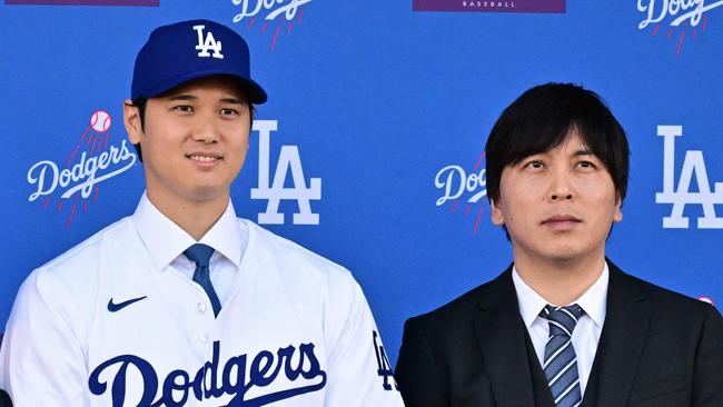 (FILES) Japanese baseball player Shohei Ohtani (C) poses with his agent Nez Balelo (L) and Japanese interpreter Ippei Mizuhara during a press conference on his presentation after signing a ten-year deal with the Los Angeles Dodgers at Dodgers Stadium in Los Angeles, California on December 14, 2023. Representatives of Shohei Ohtani said March 20, 2024 the baseball superstar had been the victim of "a massive theft," reported to involve millions of dollars allegedly stolen by the Japanese ace's interpreter to place bets with a suspected illegal bookmaker. The Los Angeles Times reported that the firm had looked into the actions of Ohtani's longtime interpreter Ippei Mizuhara after the newspaper learned that Ohtani's name had surfaced in a federal investigation of alleged illegal bookmaker Mathew Bowyer. (Photo by Frederic J. Brown / AFP)