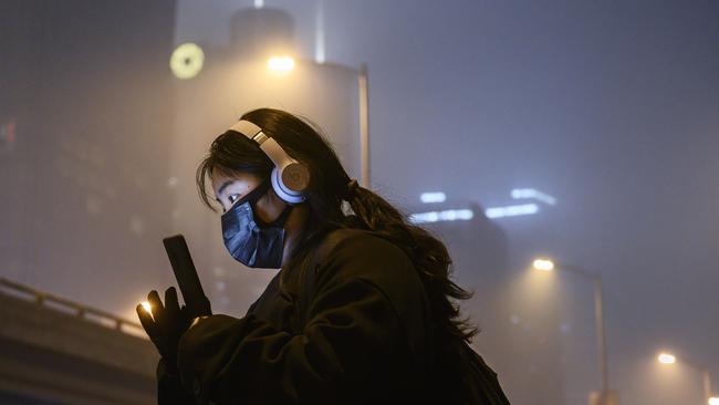 A woman wears a protective mask as she waits for a bus at a usually busy stop in Beijing, China. Picture: Getty Images