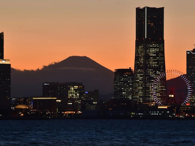 Japan's Mount Fuji is seen past skyscrapers at dusk from the Daikoku Pier Cruise Terminal, where the Diamond Princess cruise ship is anchored with over 3700 people quarantined on-board. Picture: AFP