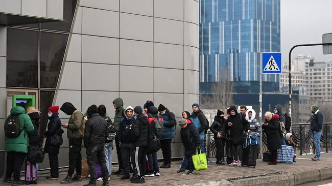 People line up to withdraw money at a cash dispenser in Kyiv.