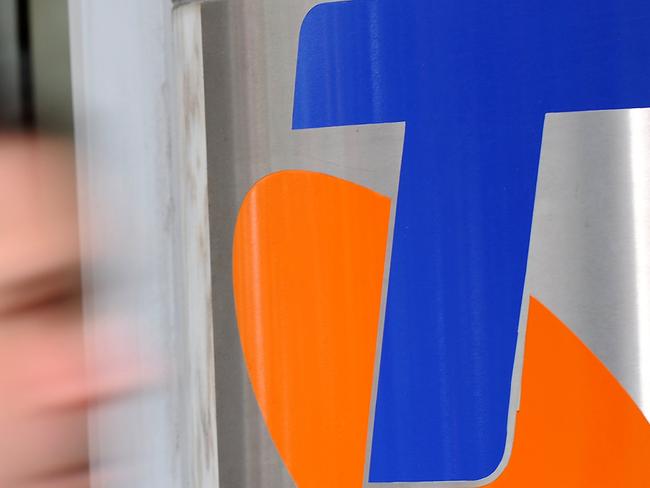 A man passes Telstra's corporate logo outside Telstra's headquarters in Sydney on September 15, 2009, as shock plans to break up the telecommunications giant were announced by the Australian government. Telstra, which is subject to strict government regulation, would be forced to split its network and wholesale arm from its retail unit unless it agrees to do so.  AFP PHOTO/Torsten BLACKWOOD