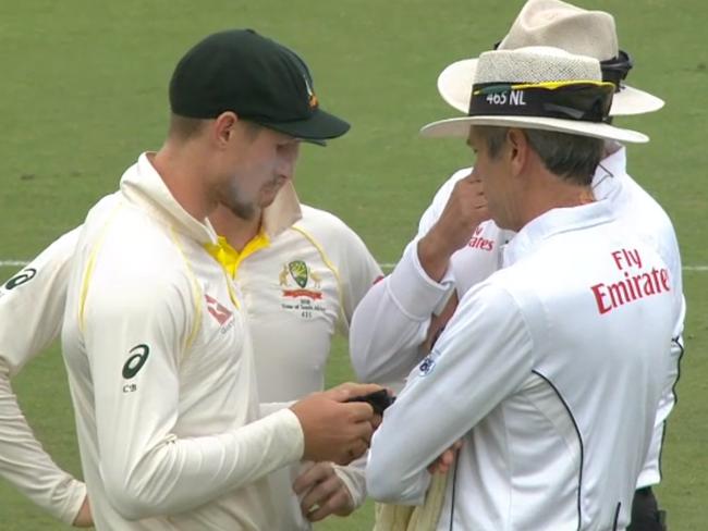 Cameron Bancroft shows the umpires his sunglass cloth after he was accused of cheating.