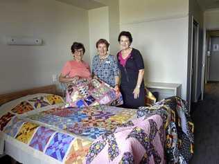 WELCOMING: Placing quilts for the opening of the Ozcare Toowoomba aged-care facility in Greenwattle St are (from left) Toowoomba Quilter Club members Fay Suley and Lee Hicks with facility manager Elizabeth Klein. Picture: Bev Lacey