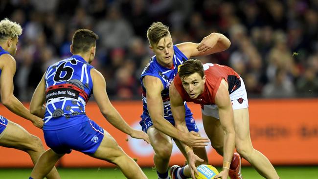 Melbourne’s Jake Lever is tackled by the Bulldogs Josh Schache at Etihad Stadium. Picture: Joe Castro/AAP