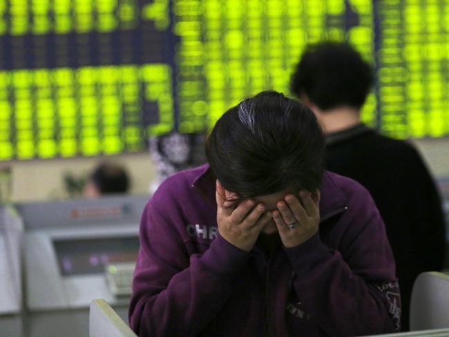 A woman rubs her face as she stands in a stock brokerage house in Nantong.