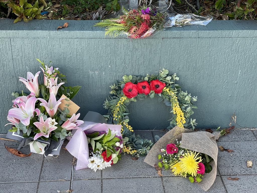 Flowers are laid beneath the two flags which are flying at half mast outside Mackay police station on Sydney St after Constable Rachel McCrow, 29, and Constable Matthew Arnold, 26 were gunned down along with a neighbour Alan Dare who was also shot and killed at Wieambilla, south of Chinchilla. Photo: Janessa Ekert