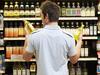 Young man in supermarket comparing bottles of oil, rear view, close-up