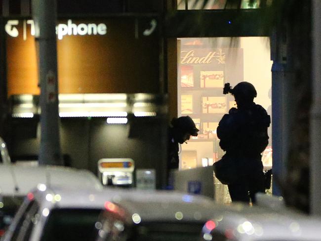 Armed tactical response officers stand ready to enter the Lindt Cafe.