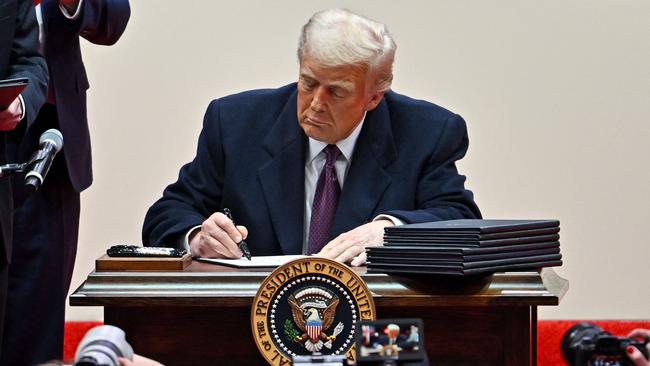 US President Donald Trump signs executive orders during the inaugural parade inside Capital One Arena, in Washington, DC, on January 20, 2025. (Photo by ANGELA WEISS / AFP)