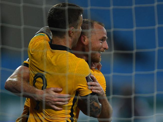 Australia's defender Rhyan Grant (R) hugs teammate Adam Taggart after scoring during the FIFA World Cup Qatar 2022 qualifying round Group B football match between Australia and Vietnam at the My Dinh National Stadium in Hanoi on September 7, 2021. (Photo by Manan VATSYAYANA / AFP)