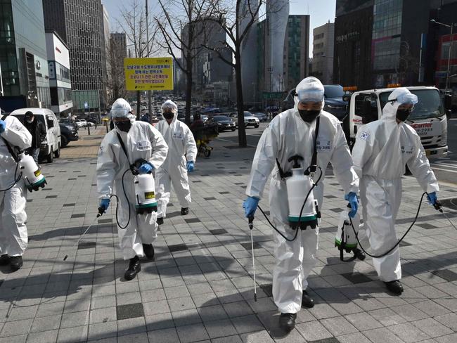 TOPSHOT - South Korean soldiers wearing protective gear spray disinfectant on the street to help prevent the spread of the COVID-19 coronavirus, in Seoul on March 6, 2020. - South Korea's total reported infections -- the largest figure outside China, where the coronavirus first emerged -- rose to 6,284 on March 6, the Korea Centers for Disease Control and Prevention said. (Photo by Jung Yeon-je / AFP)