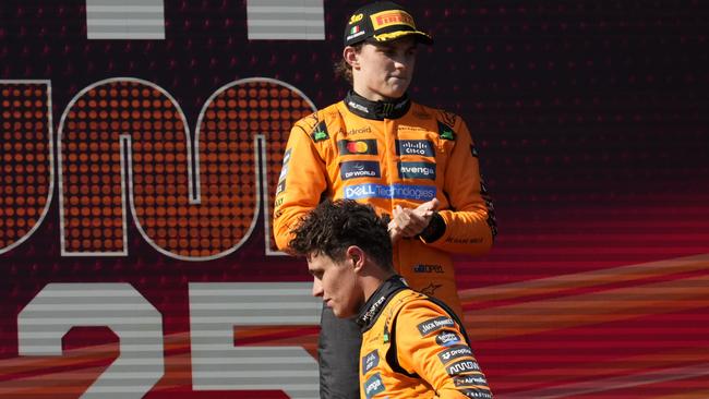 Piastri is in deep thought as his team-mate Lando Norris walks past the podium.