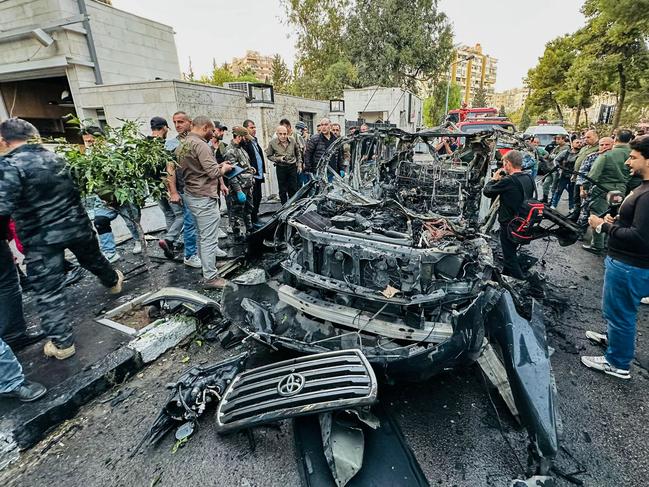 TOPSHOT - Syrian emergency and security services inspect the wreckage of a car that exploded in  Damascus on October 21, 2024. Syrian state media said a car exploded on October 21 in the Mazzeh neighbourhood of Damascus which is home to embassies and security headquarters but it did not specify the cause of the blast. (Photo by Maher AL MOUNES / AFP)