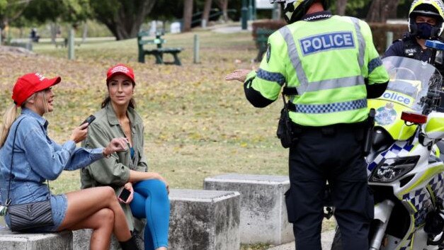 Police speak to unmasked women during a protest in Brisbane's New Farm Park. Picture: Liam Kidston