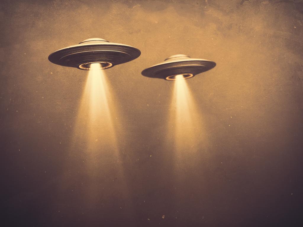 Two UFOs flying in fog with light below. 3D illustration monochromatic sepia-toned old-time photography. Concept image with blank space below the UFOs for texts and image.