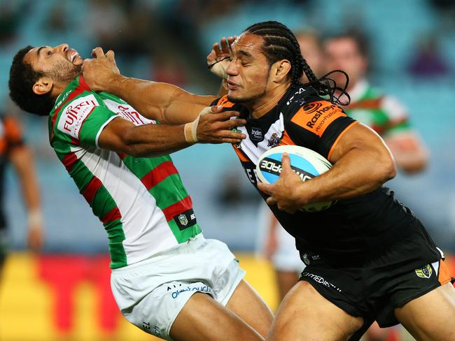 Tigers Martin Taupau fends off South Sydney's Alex Johnston to score a try.