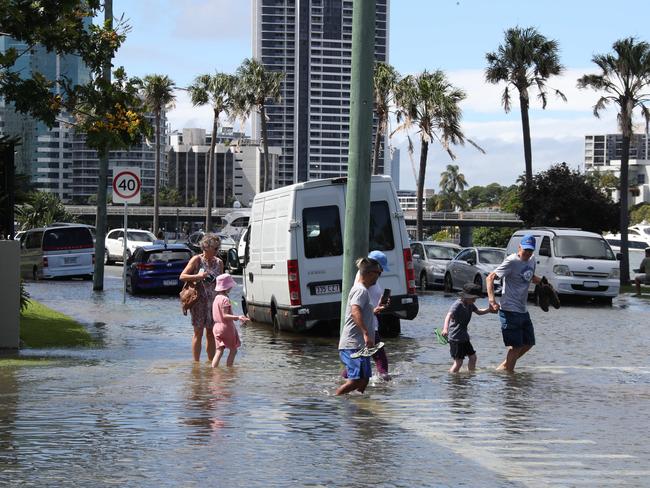 Flooding from the King tide at Budds Beach at Surfers Paradise was made worse by the approaching storm system. People wading through the floodwaters.. Picture Glenn Hampson