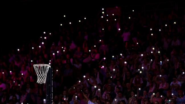 Fans hold torches as a power cut affects parts of the stadium during the round two Super Netball match between Adelaide Thunderbirds and NSW Swifts.