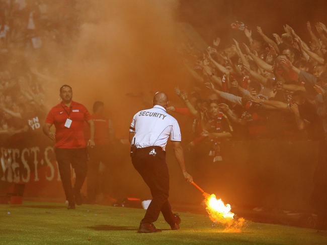 A security guard grabs a flare lit by fans during the Round 18 A-League match between Sydney FC and the Western Sydney Wanderers at Netstrata Jubilee Stadium in Sydney, Friday, February 28, 2020. (AAP Image/Brendon Thorne) NO ARCHIVING, EDITORIAL USE ONLY