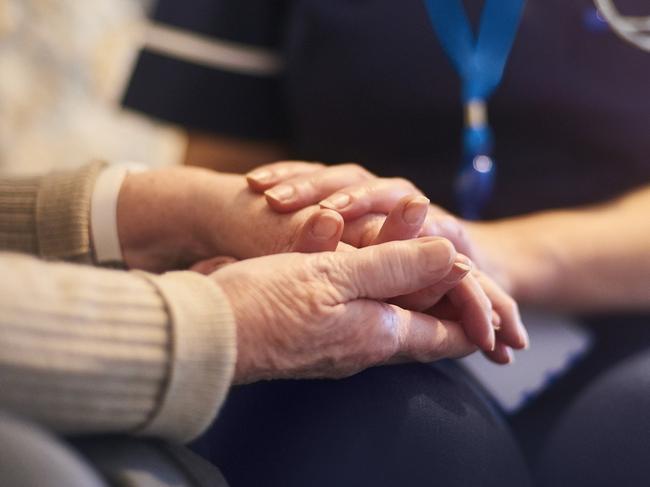 A female nurse consoles a senior patient at home, aged care generic