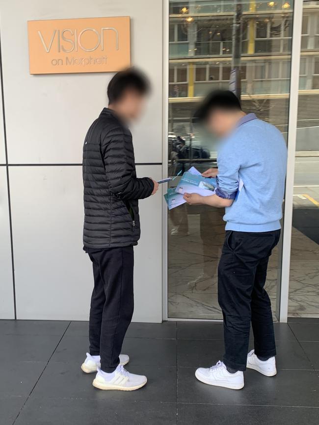 Two people with a wad of ballot papers outside the Vision Apartment building. Picture: Supplied