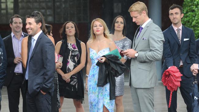 Friends and family shelter from the rain while waiting for buses to take them to the wedding location. Picture: Simon Bullard