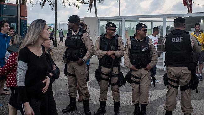 Tourists pass by as police stand guard along Copacabana Beach. Photo: Chris McGrath/Getty Images